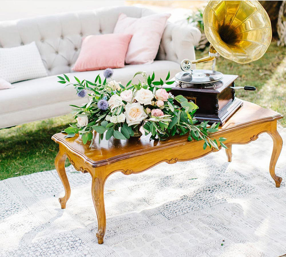 Gramophone sitting on a wooden table next to a bouquet of flowers