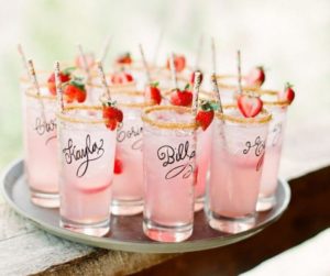 Cocktails in tall glasses with straws and strawberries on the rim