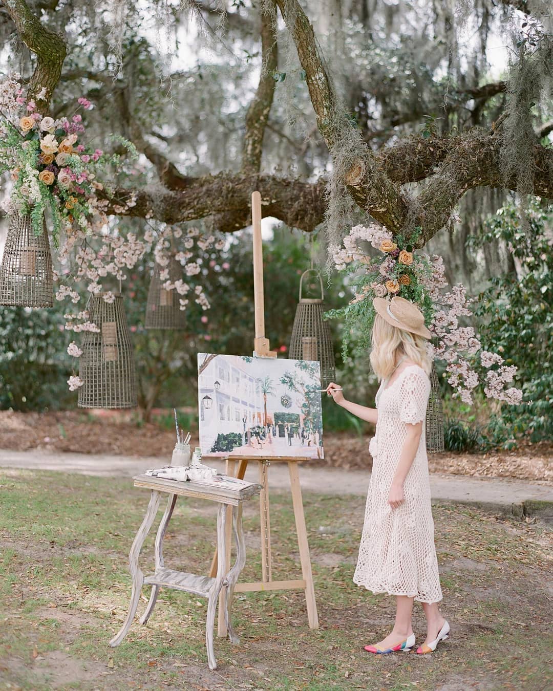 live painter wedding reception beneath live oaks with floral pendants hanging