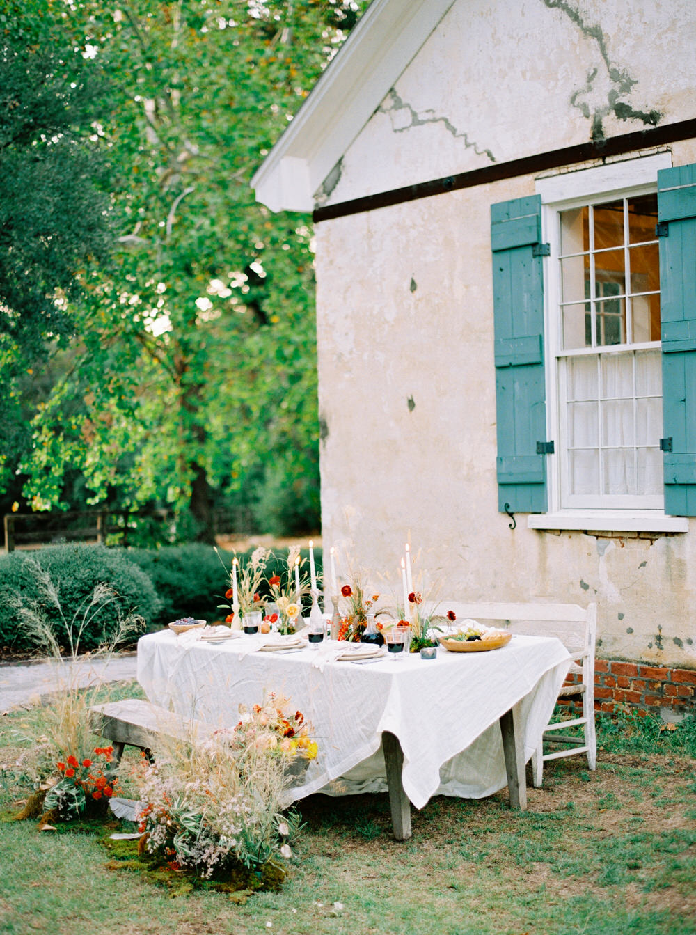 cozy autumn outdoor dinner table with wild foraged flowers, earthenware and handcarved wood table decor and ambient candlelight