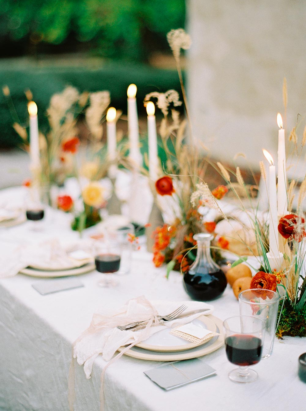 cozy autumn outdoor dinner table with wild foraged flowers, earthenware and handcarved wood table decor and ambient candlelight