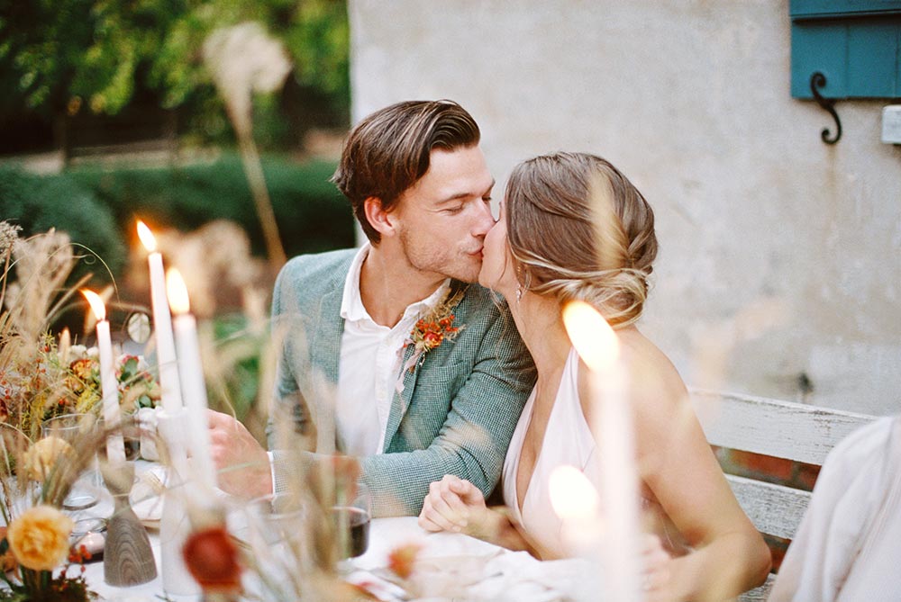 autumn al fresco wedding dinner with wild flower table decor, a groom in sage green suit and bride in apricot silk gown