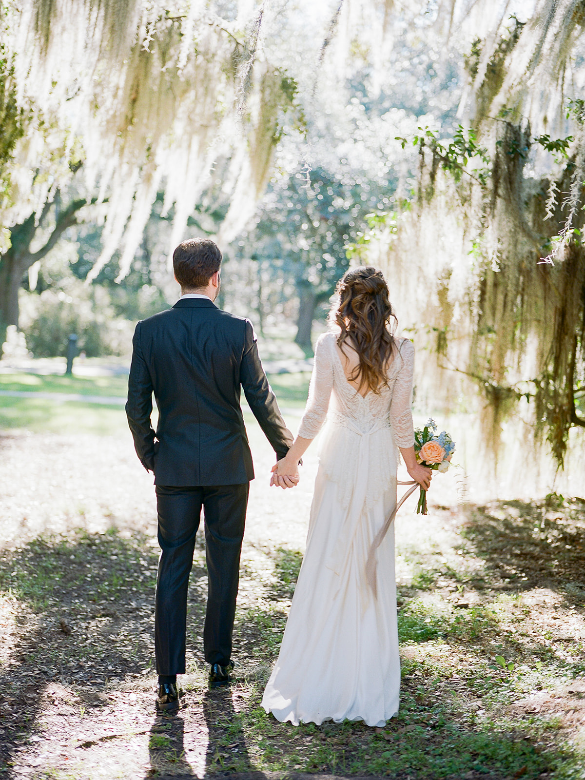 Charleston microwedding with a bride in a long-sleeve lace and beaded wedding dress inspired by a vintage silhouette holding an Icelandic poppy bouquet with roses and sweet pea; planning and design by Willow and Oak Events with photography by Kylee Yee