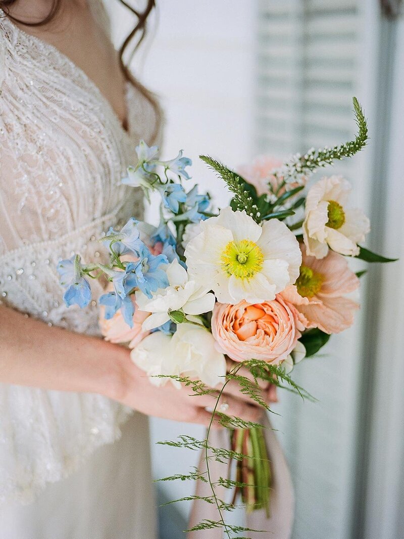 Early spring wedding in Charleston, SC at Legare Waring House with bride in a beaded lace, long-sleeve, vintage inspired wedding dress holding a petite bridal bouquet with Icelandic poppies and sweet pea, styling by Willow and Oak Events and photography by Kylee Yee