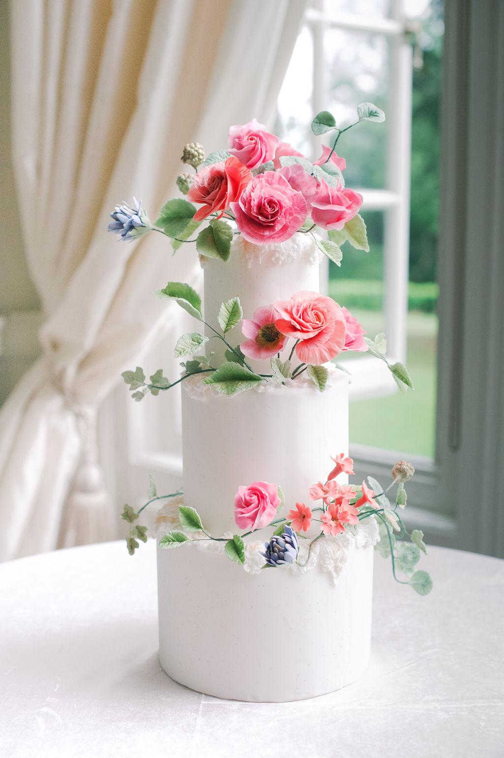 three tiered wedding cake with colorful 3D sugar flowers; photography by Julie Livingston at an English country estate Hedsor House with planning and design by Willow and Oak Events