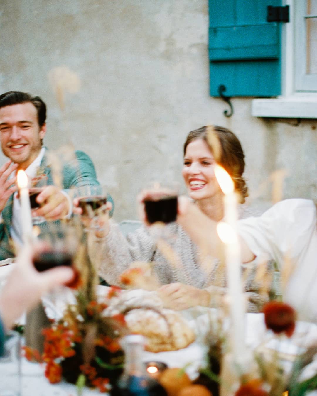 intimate wedding in South Carolina with bride in an apricot wedding dress and beige sweater and groom in a sage green wool suit, toasting with wine; captured by Brian D Smith Photography and planned + styled by Willow and Oak Events