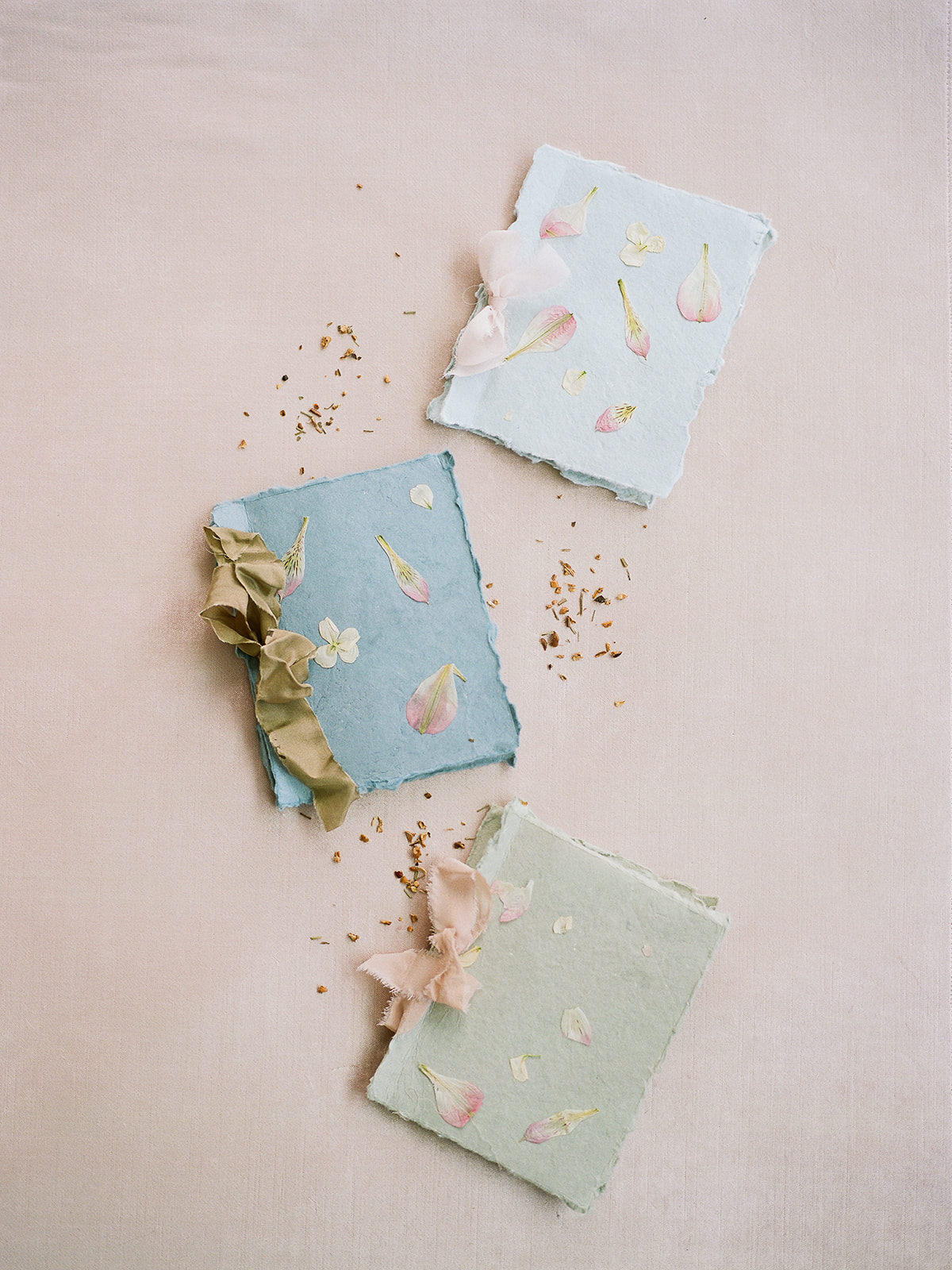 Pressed flower vow booklets on handmade paper with silk ribbon bows, created by Willow and Oak Events and captured by Kylee Yee Photography