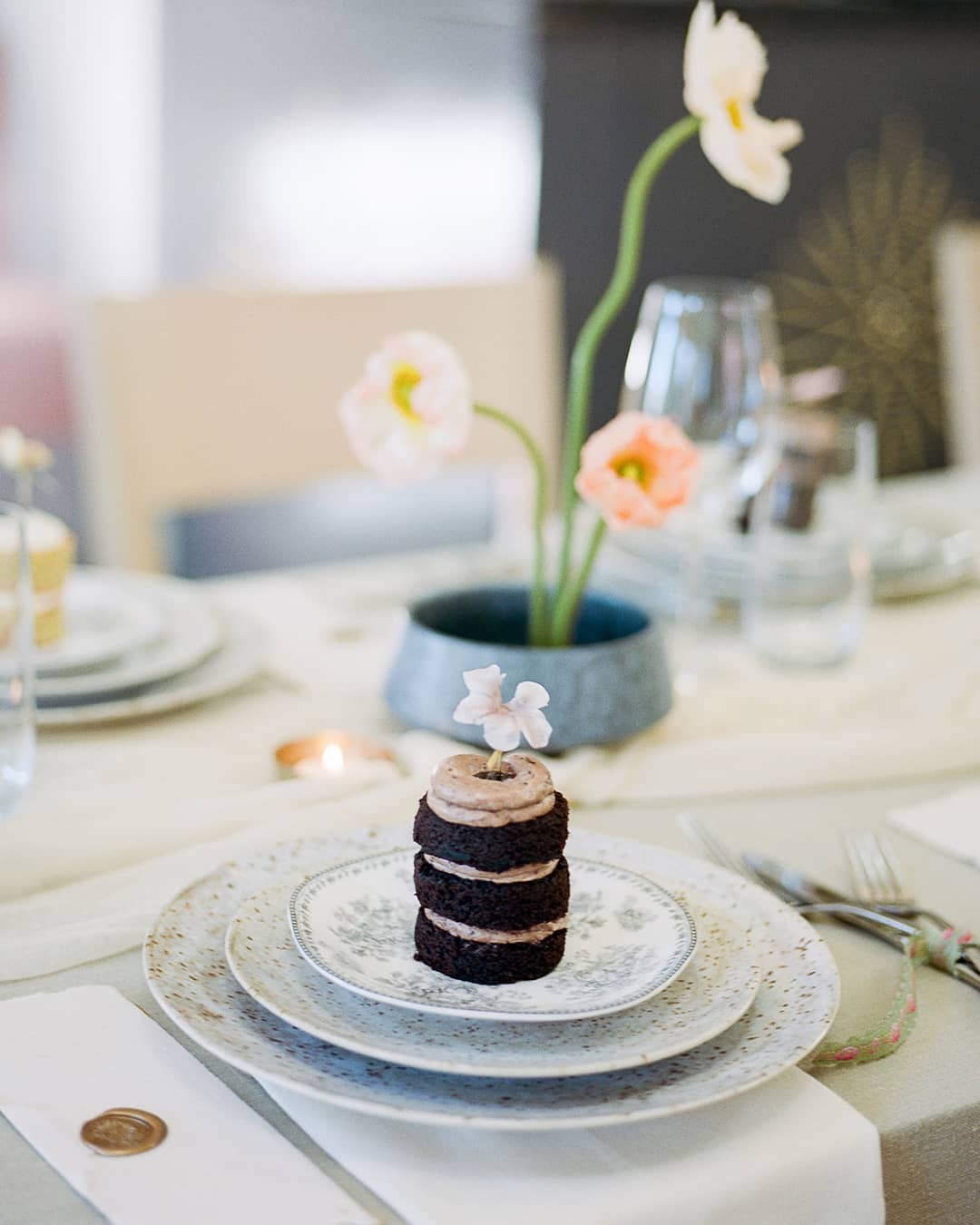 Mini chocolate cake with a sugar flower on toile and speckled dinnerware from an Icelandic poppy filled Charleston microwedding, planned and designed by Willow and Oak Events // Photo by Kylee Yee Photography