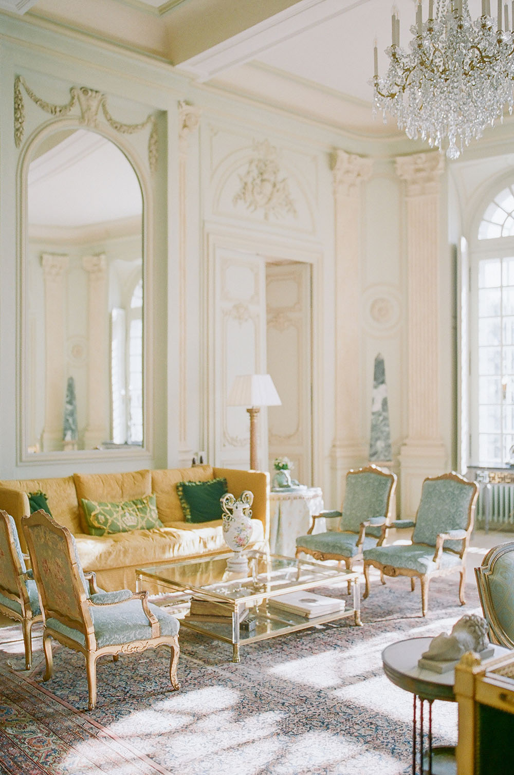 The interior salon of Chateau du Grand Luce in the Loire Valley, with antique French upholstered chairs and a mustard yellow sofa