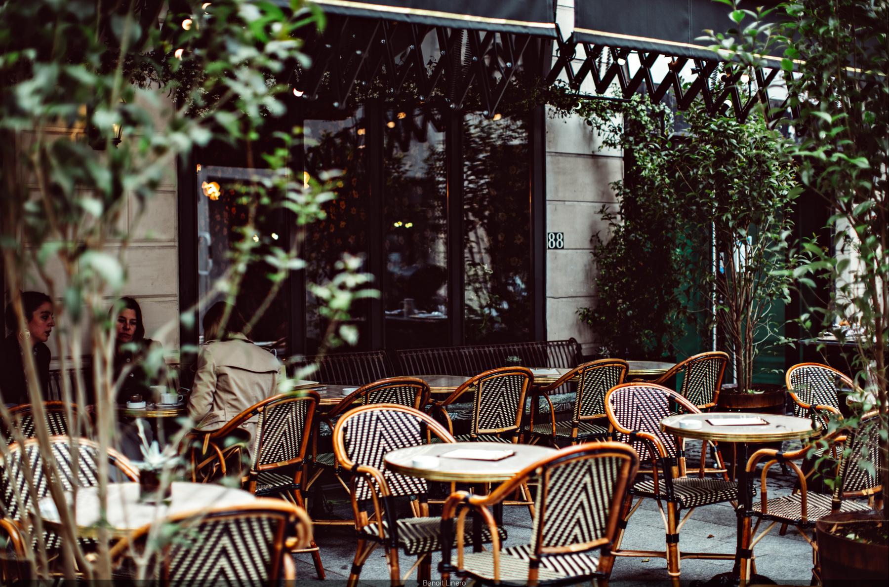 Striped rattan bistro chairs beside round marble tables at Hotel Providence's outdoor restaurant terrace