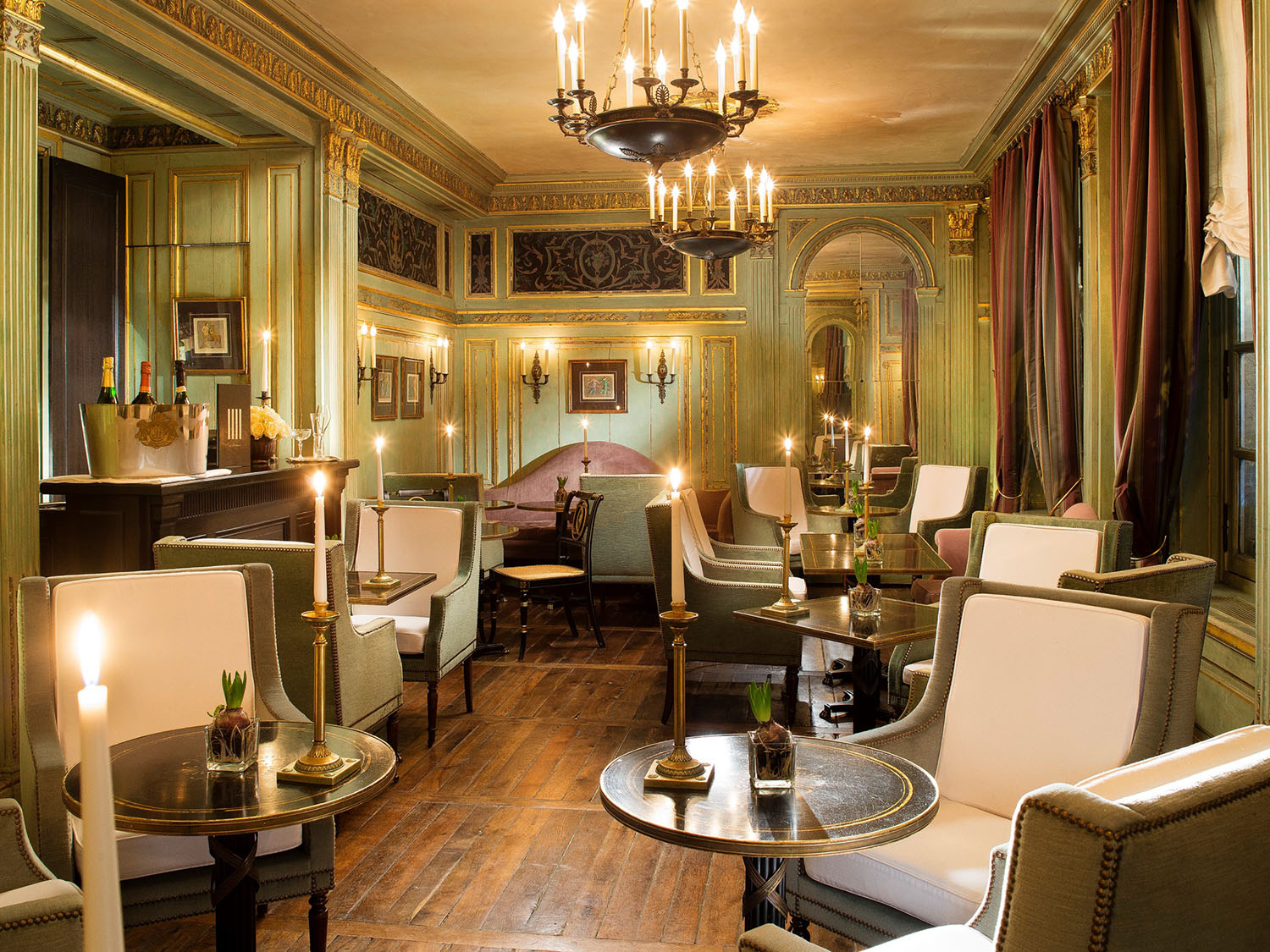 The Belle Epoque style Champagne Bar at Le Dokhan's in Paris with velvet green chairs, dusty pink drapes and original sage + gold moldings along the walls