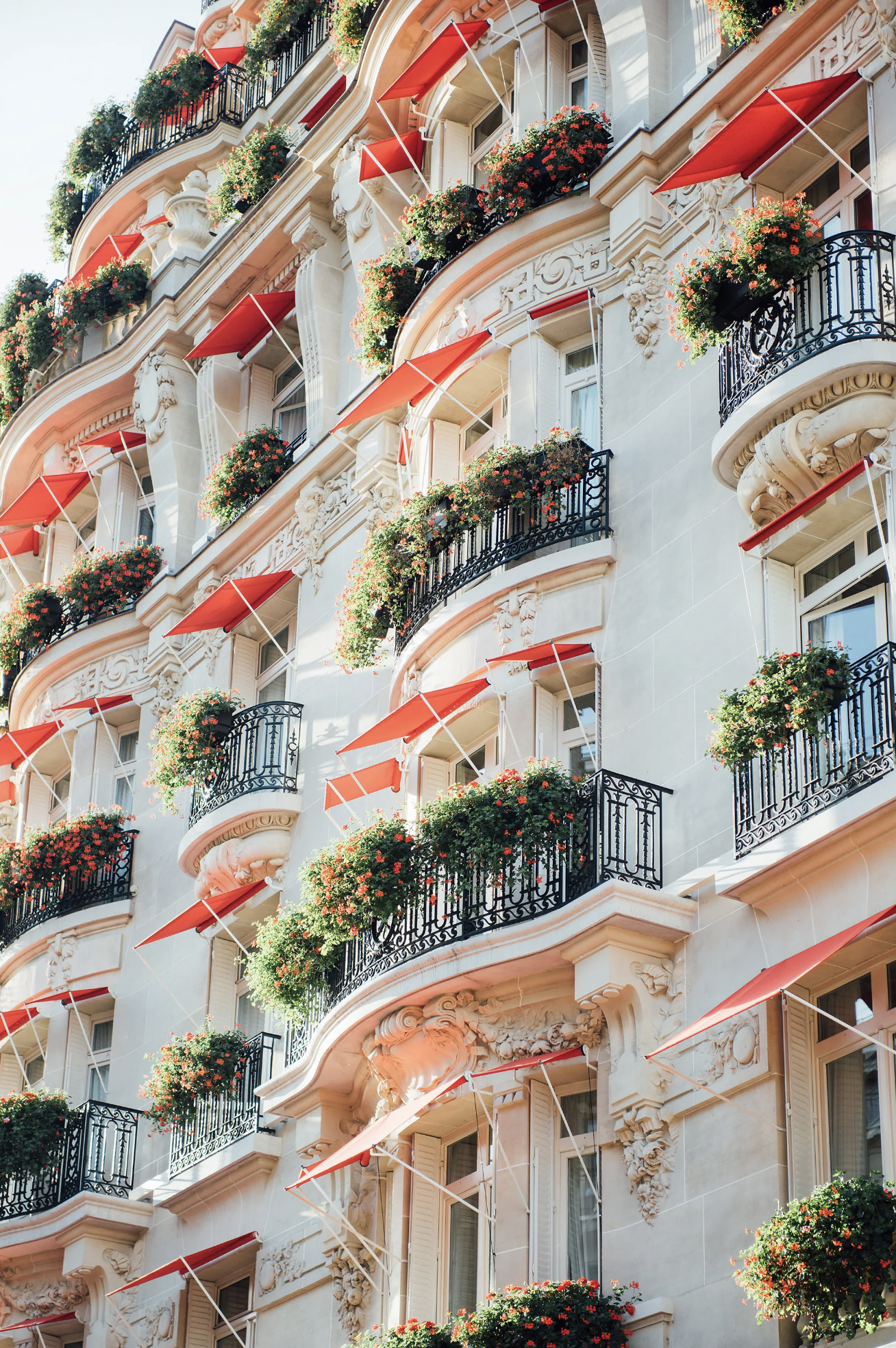 The Art Deco style exterior of Hotel Plaza Athénée with alabaster stone, iron terraces, 2000 red geraniums and signature red awnings