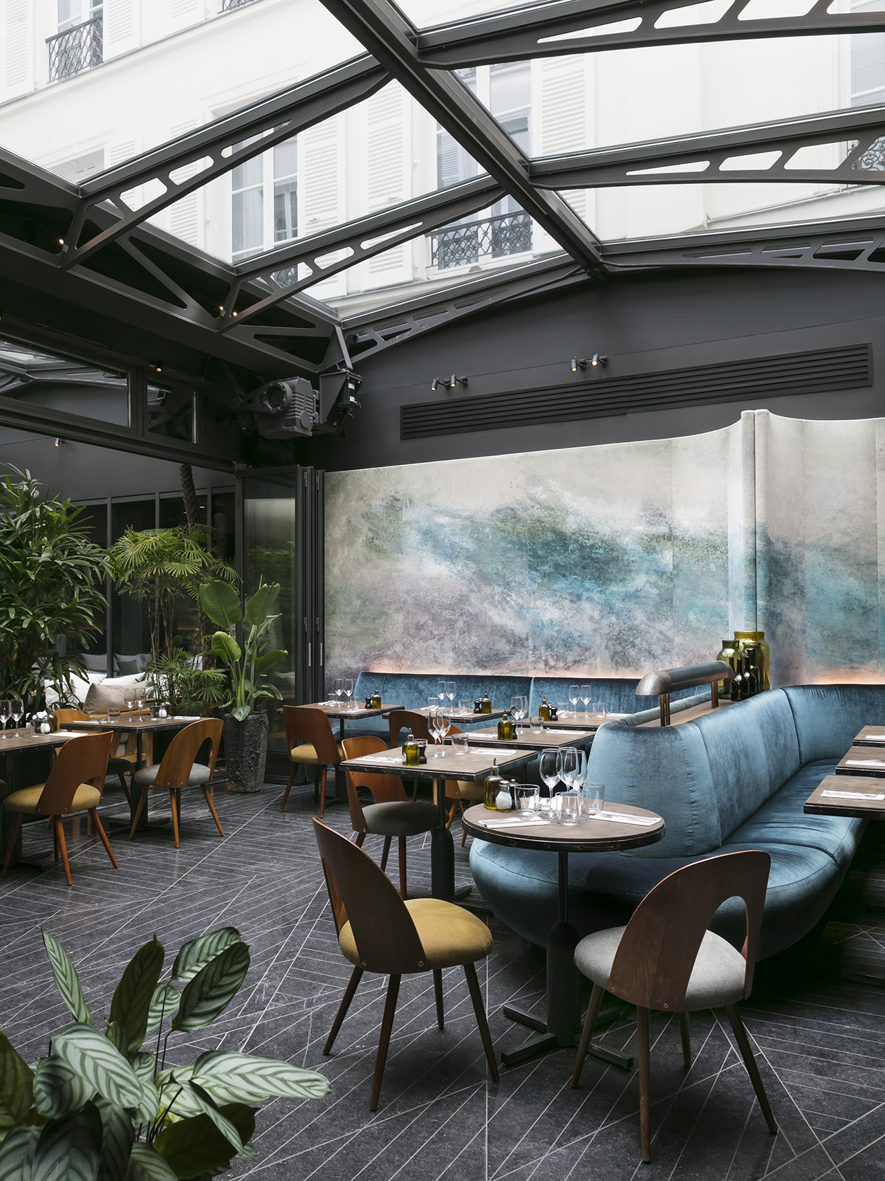 A blue-green sci-fi style restaurant with a retractable ceiling and abstract panel art at Hôtel National des Arts et Métiers in Paris