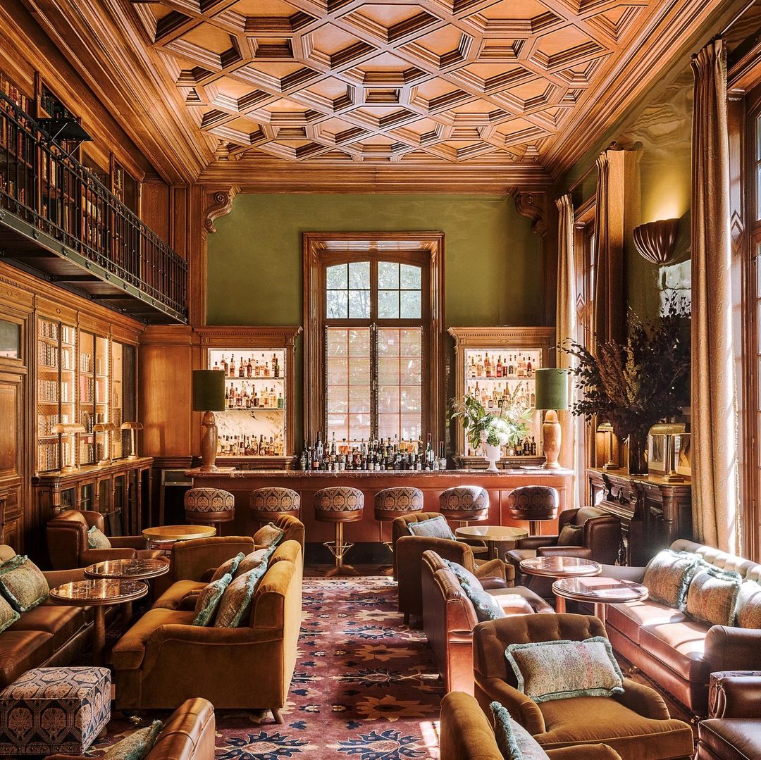 The library bar at Saint James Paris featuring wood paneling, cozy velvets and time-worn leathers