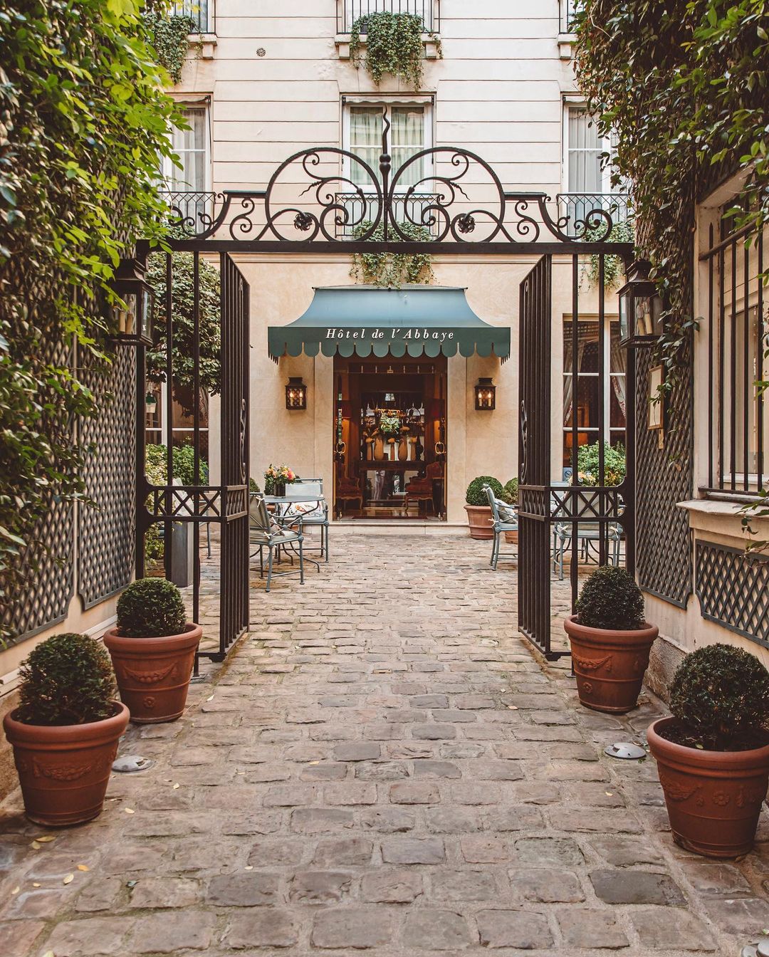 The hidden entrance to Hôtel de l'Abbaye in Paris with its metal green awning, original cobblestone courtyard and ornate iron gate