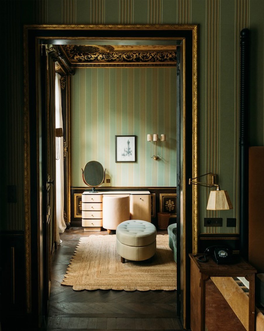 A green and gold striped wallpaper for a suite at Soho House Paris with a pale pink vanity