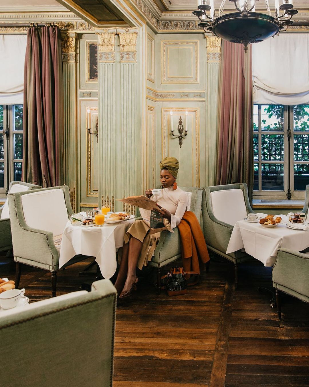 The Belle Epoque style Champagne Bar at Le Dokhan's in Paris with velvet green chairs, dusty pink drapes and original sage + gold moldings along the walls