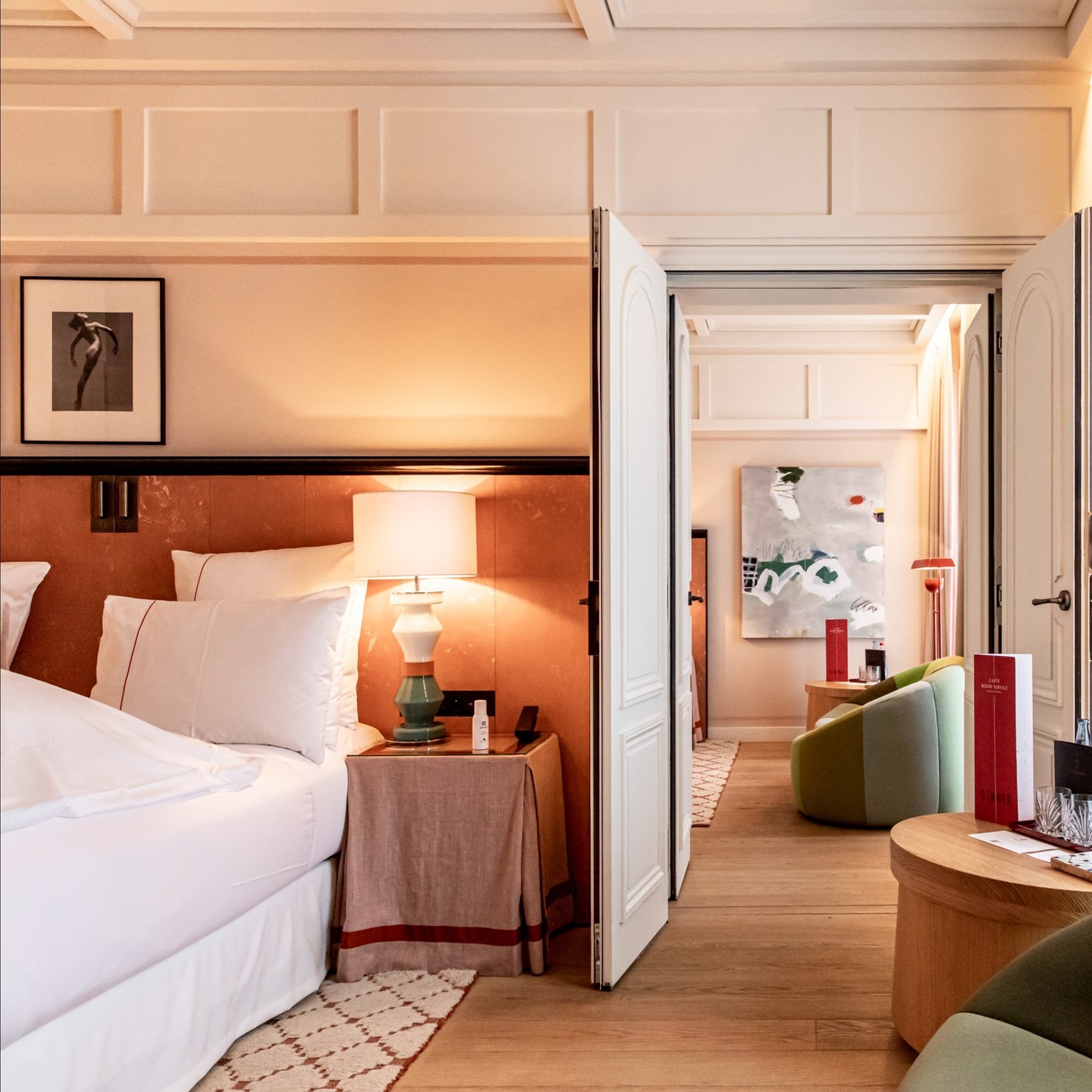 A large suite at Hotel Sinner with an orange, sage and ruby red color scheme