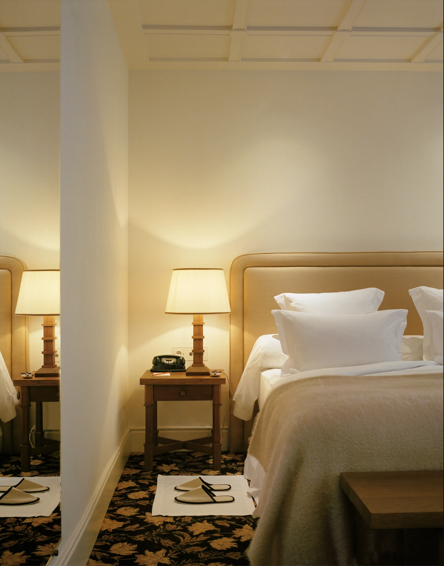 A warm-hued bedroom at Chateau Voltaire with a black and golf leafy print carpet