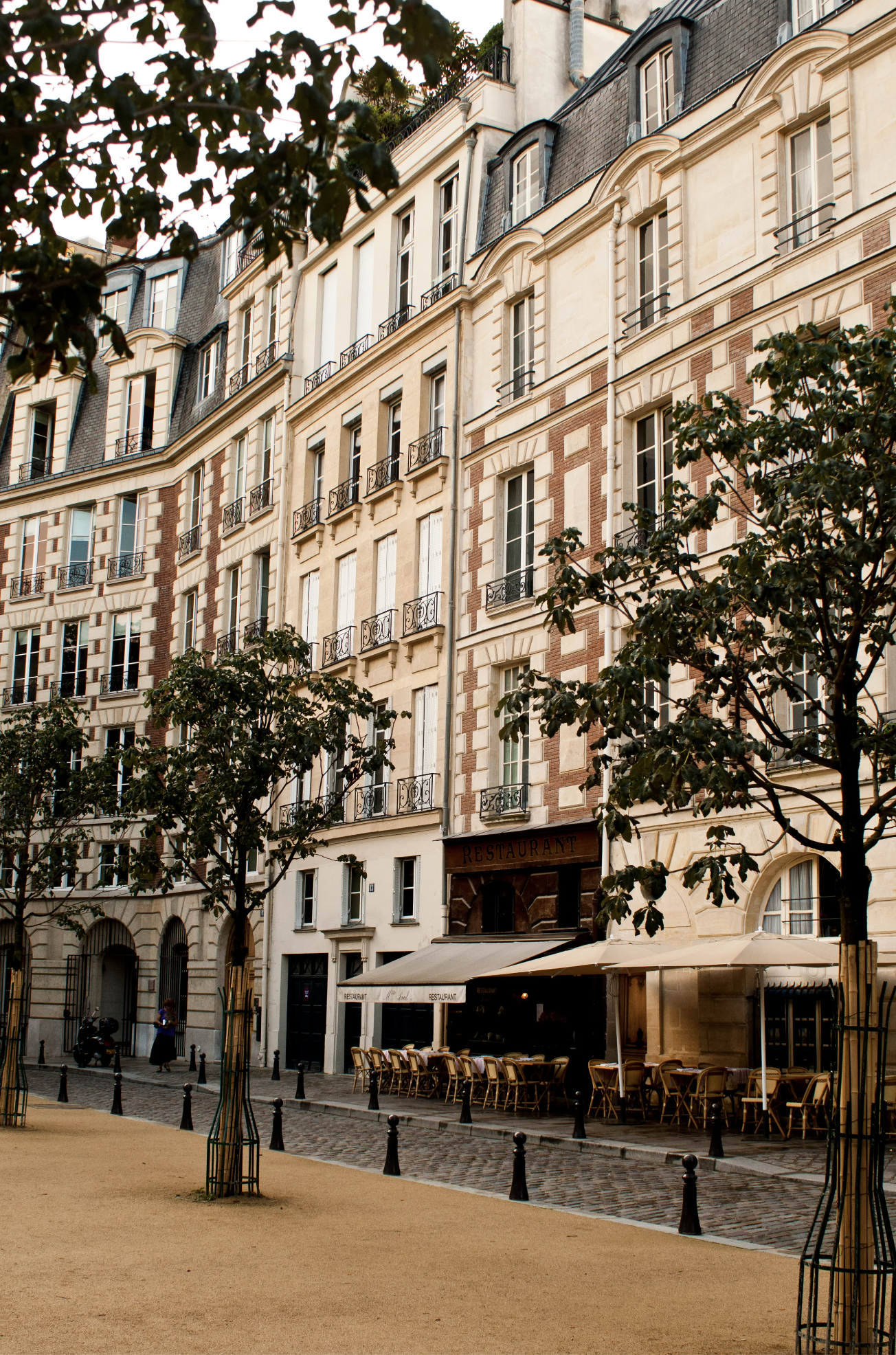 The brick + limestone exteriors of townhouses and apartments in Place Dauphine