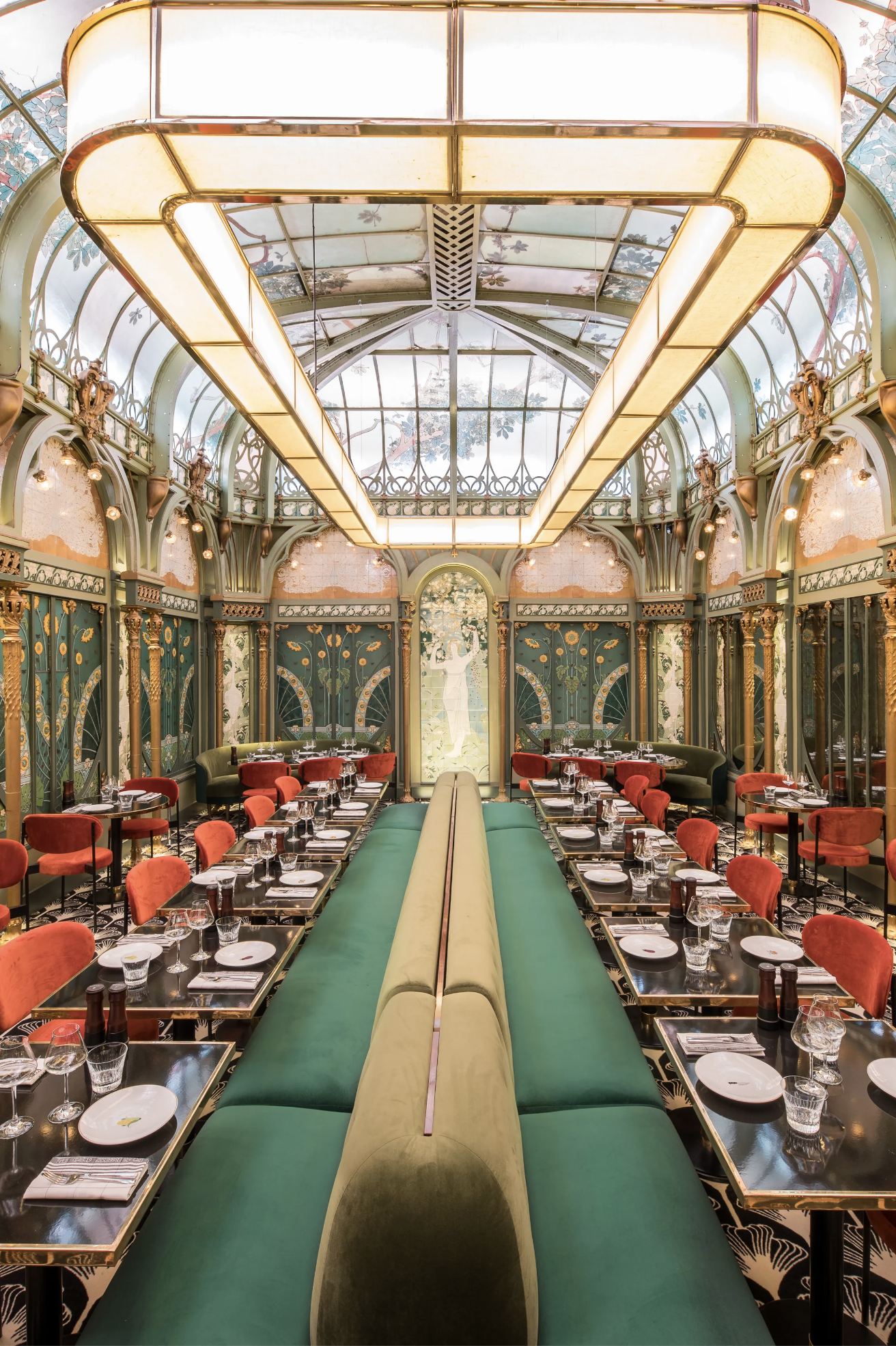 the dramatic Art Nouveau interiors of Beefbar Paris with olive green and ruby red velvet banquette seating, tile mosaics and a vaulted glass atrium ceiling