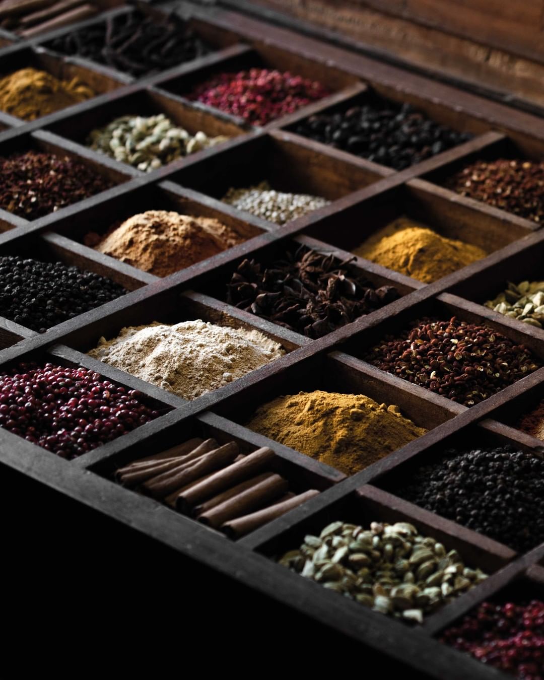 A mahogany-stained spice drawer with dozens of compartments for loose exotic spices