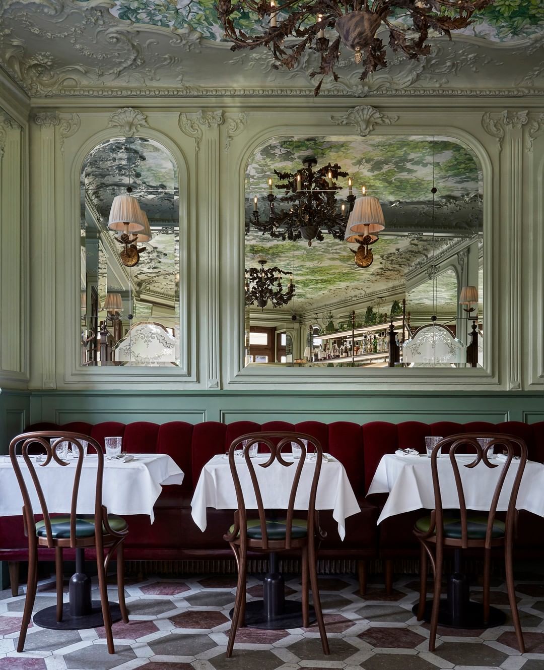 Belle Epoque interiors of Le Chardenoux with mirrored walls, painted ceilings, wooden bentwood chairs and red velvet sofa seating