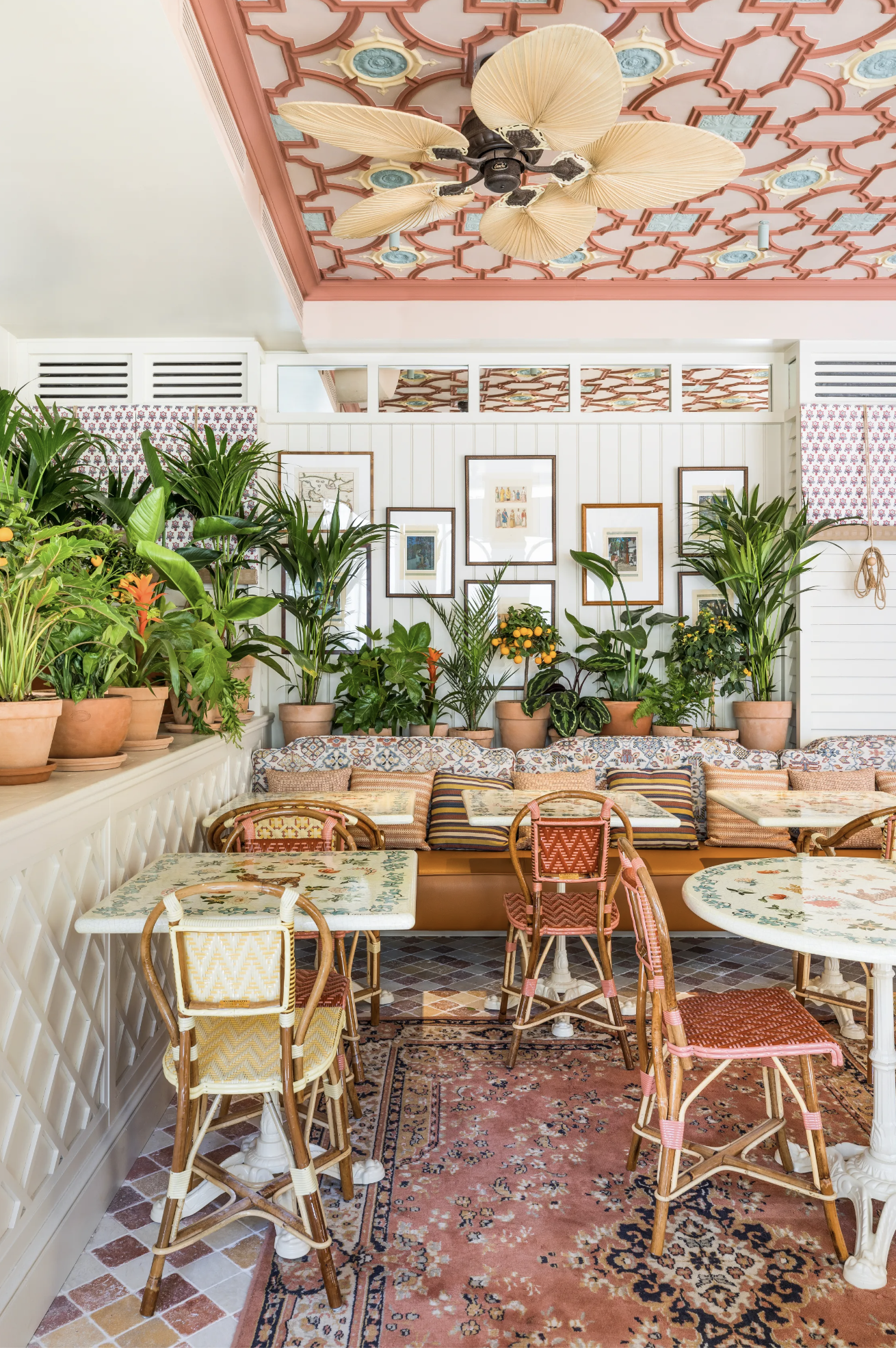 Bahamian beach interior design aesthetic at Sir Winston in Paris with yellow and pink rattan café chairs, hand-painted tables and exotic potted fruit trees