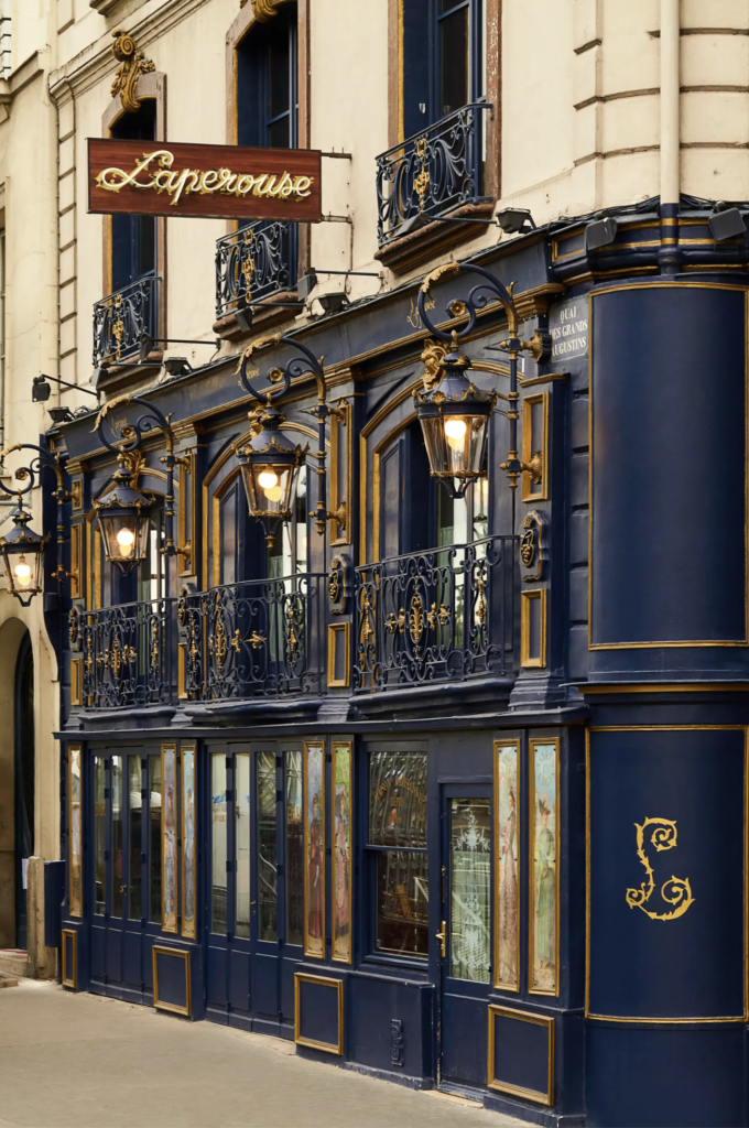 Polished navy and gold exterior of Laperouse with Belle Epoque lanterns and scripty lettering