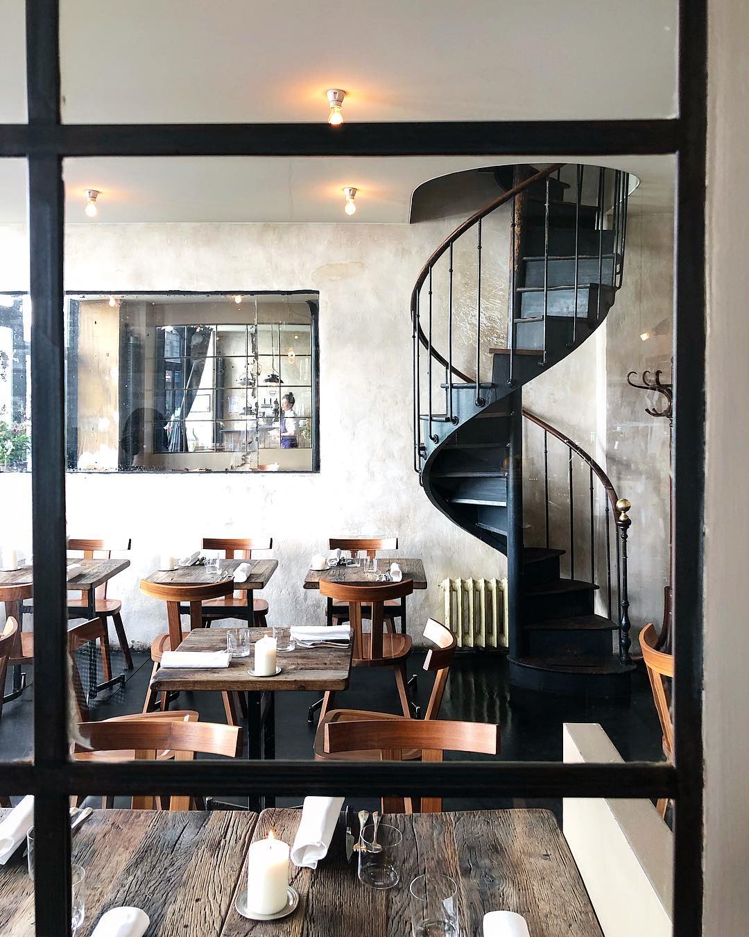 The Scandinavian style interiors of Septime with rustic wooden tables, simple wooden chairs and a black spiral staircase 