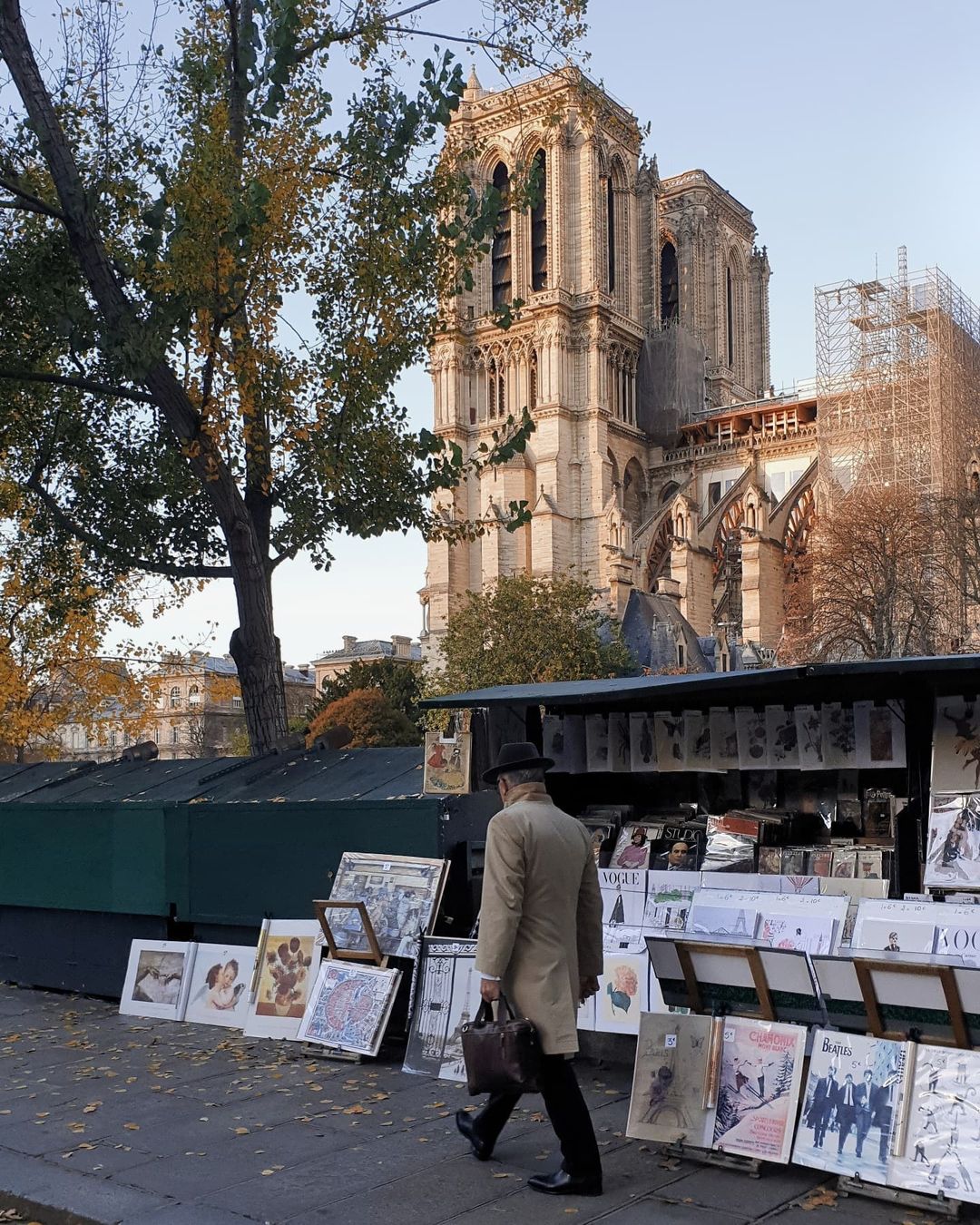 A man walks by the street vendors hawking vintage inspired art and antique books in Paris while the Notre Dame sits in the background