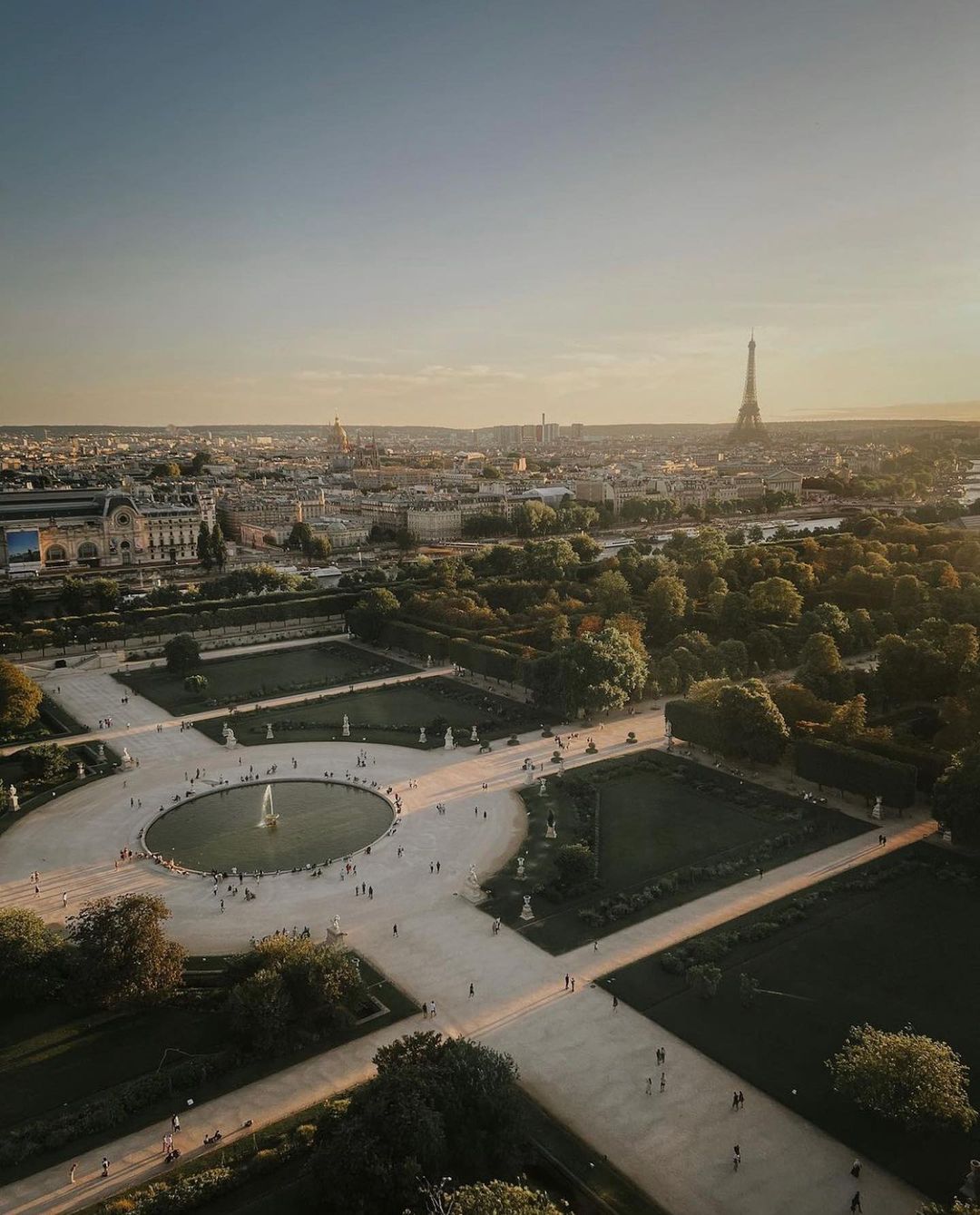 A bird's eye view of Jardin des Tuileries with a large fountain in the middle and the Eiffel Tower in the background
