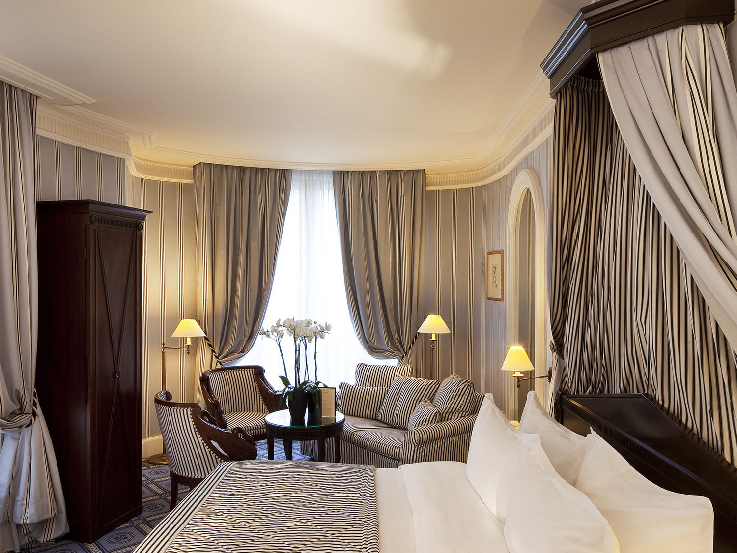 A navy and white guest room at Le Dokhan's Paris with a ticking stripe pattern and classic lighting